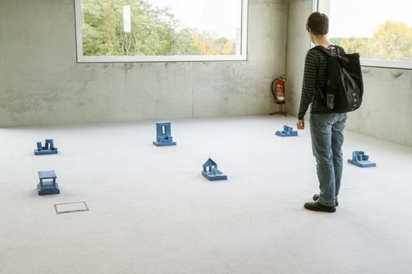 A visitor looks at the blue monochrome objects.