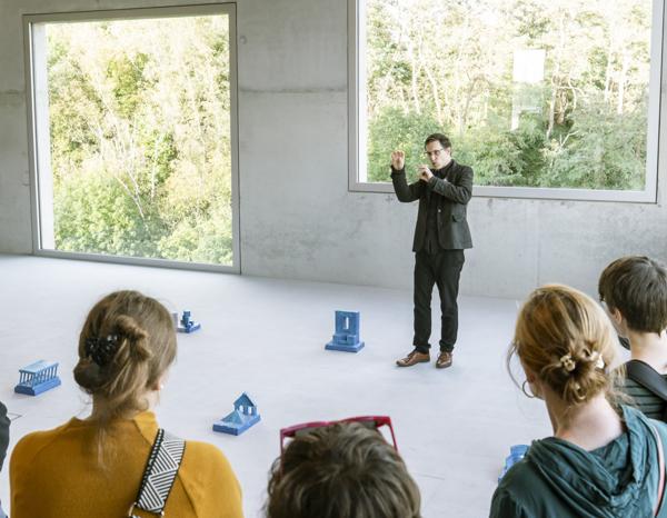 Robert J. Tomsons conveys the message of the blue monochrome objects to visitors to the Spacesthetics exhibition.